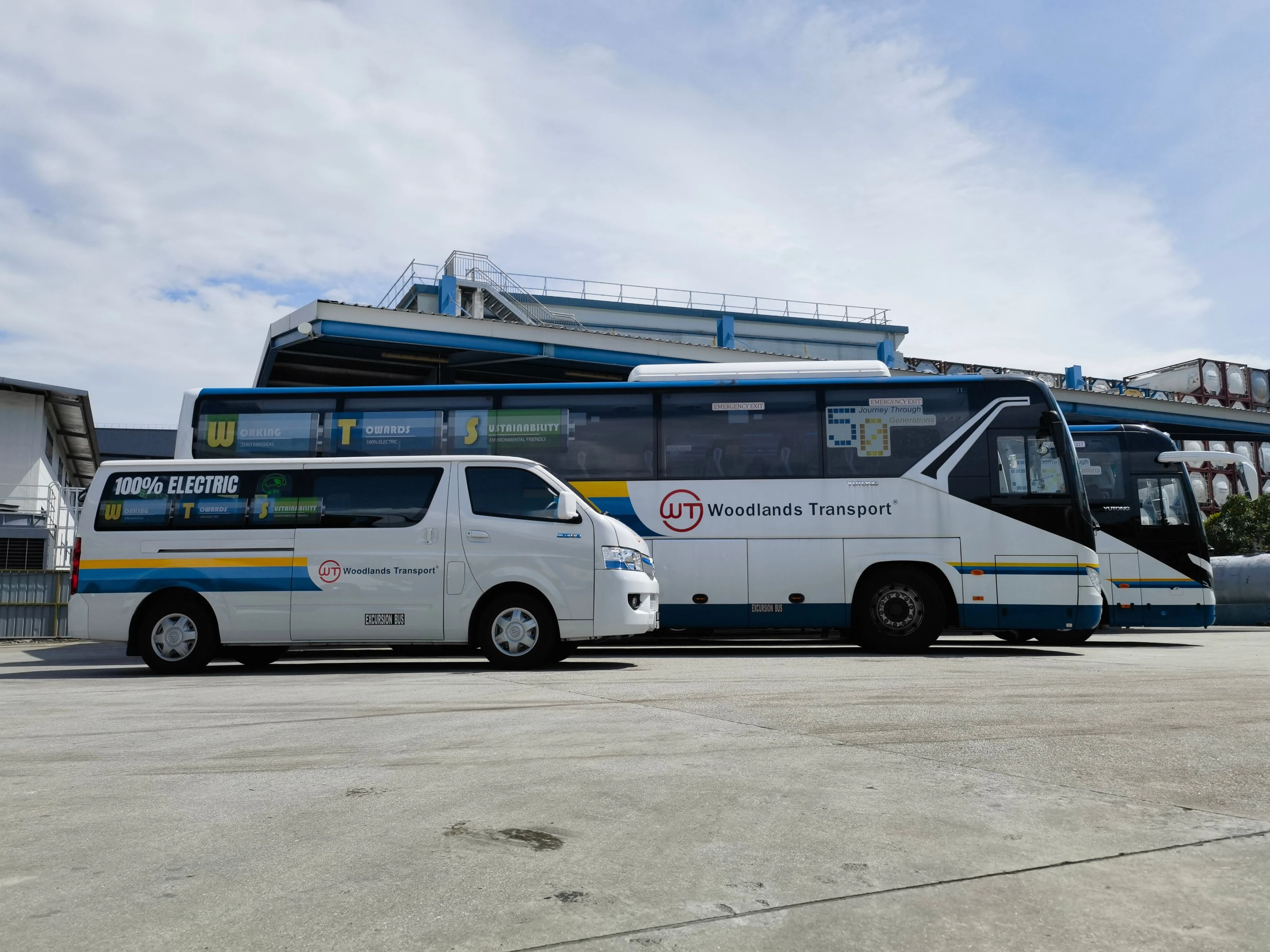 Woodlands Transport electric van and coaches lined up at the Gul Circle depot